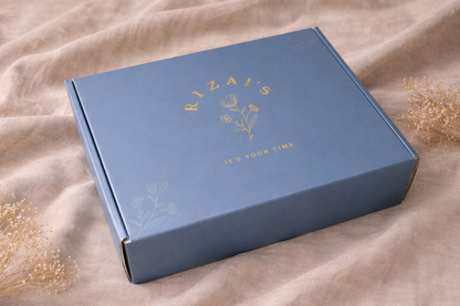 Rizai's gift box with gold foil text on a beige fabric background