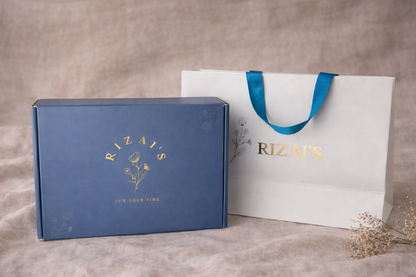Rizai's gift box with gold foiling and gift bag with 'Rizai's' branding on a textured surface.