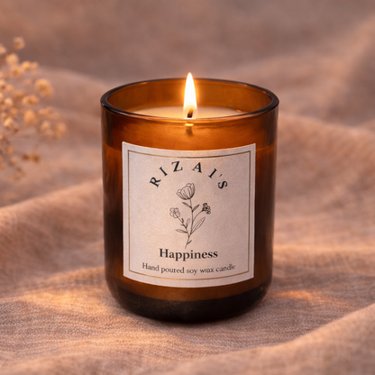 Rizai's Happiness candle in a amber jar with a label on a textured fabric background